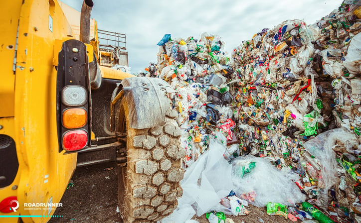 a bulldozer pushes trash in a landfill