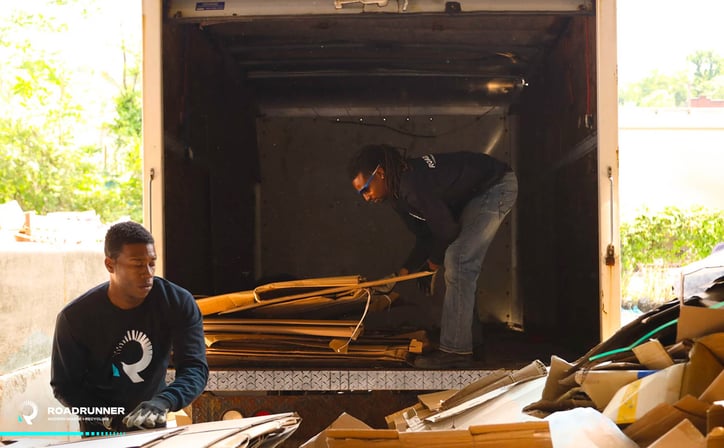 two RoadRunner employees sort cardboard at a recycling center
